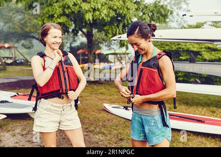 Les jeunes femmes mettent leur gilet de sauvetage en préparation pour le voyage en kayak Banque D'Images