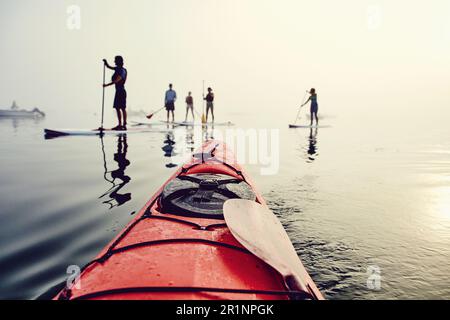 Un groupe de paddle-boarders et de kayakistes de stand-up sur un matin brumeux Banque D'Images