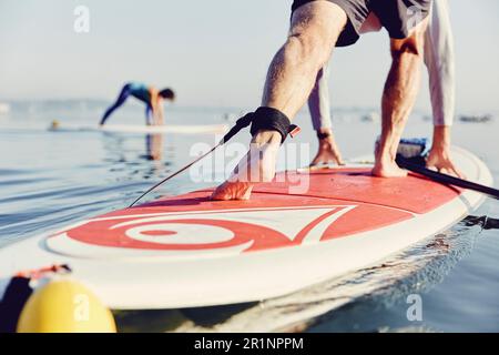Une paddle boarder de stand-up se balance dans une posture de yoga au lever du soleil dans le brouillard Banque D'Images