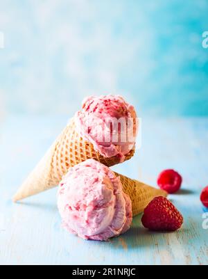 Crème glacée à la framboise en cône de cachets sur fond bleu Banque D'Images