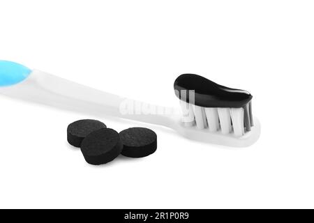 Brossez avec du dentifrice au charbon de bois et des pilules noires sur fond blanc Banque D'Images