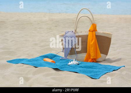 Serviette bleue, sac et accessoires de plage sur sable Banque D'Images