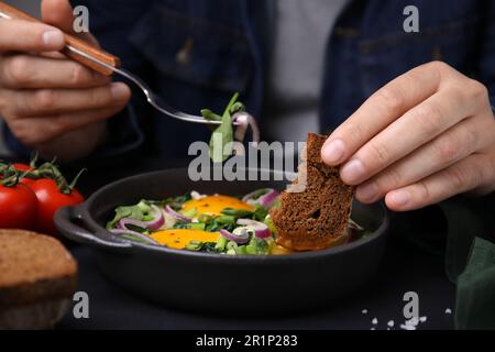 Femme trempant un morceau de pain dans le jaune d'œuf, gros plan. Manger un Shakshuka savoureux Banque D'Images