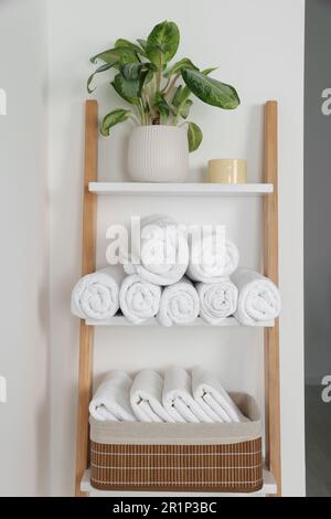 Serviettes souples sur l'échelle décorative près du mur blanc Banque D'Images
