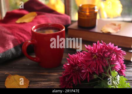 Belles fleurs de chrysanthème, une tasse de boisson chaude et des livres sur une table en bois. L'automne encore la vie Banque D'Images