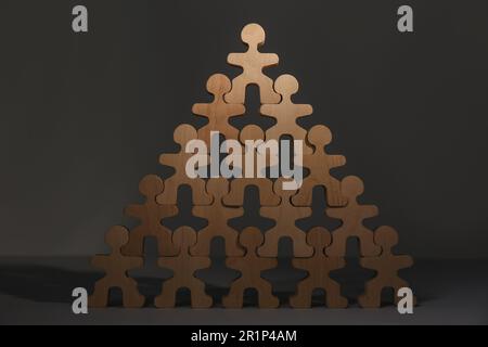 Processus de recrutement, concept de concours d'emploi. Pyramide de figures humaines en bois avec un visible sur le dessus comme premier demandeur sur la table grise Banque D'Images