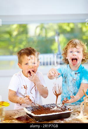 Portrait, pâtisserie et enfants avec des amis désordonnés dans la cuisine ensemble, s'amuser avec les ingrédients tout en cuisinant. Les enfants, la nourriture et cuire au four avec naughty Banque D'Images