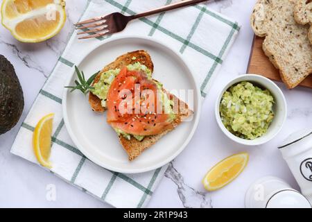 Toast avec avocat et saumon fumé arrosé de graines de sésame en haut de la table en marbre - saine alimentation Banque D'Images