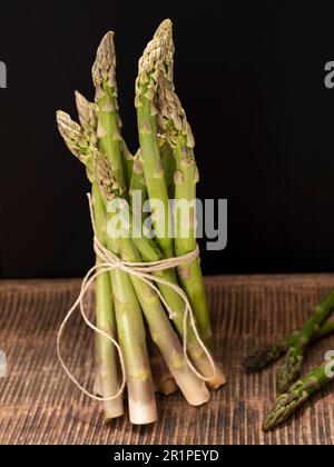 un bouquet d'asperges vertes fraîches sur un vieux panneau en bois Banque D'Images