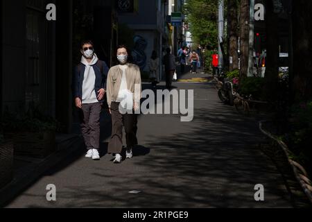 Un couple japonais marchant dans la rue portant des masques chirurgicaux. Roppongi, Tokyo, Japon. Banque D'Images