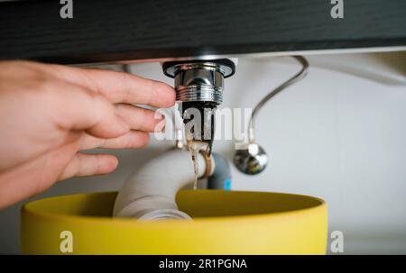 Point de vue personnel - Une personne nettoie un drain bouché de lavabo causé par l'accumulation de cheveux et de saleté, dans la salle de bains. Banque D'Images