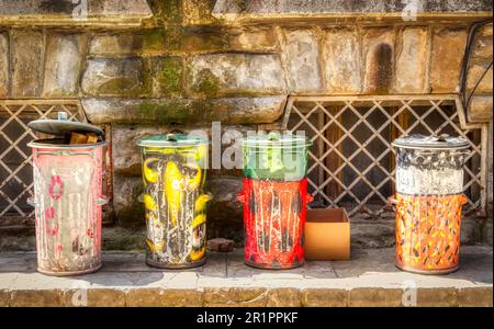 Quatre poubelles peintes dans une rue de Veliko Tarnovo, Bulgarie. La peinture est devenue fanée et usée avec le temps. Banque D'Images