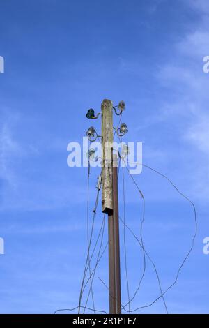 Ancien poteau téléphonique désaffecté avec des câbles coupés avec ciel bleu à la verticale Banque D'Images