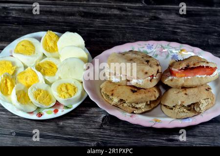 Une assiette de tranches d'œufs durs et de sandwiches au fromage blanc Feta avec des tranches de tomates et des tahini halva ou Halawa Tahiniya Banque D'Images