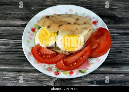 Mini pain plat traditionnel égyptien avec son de blé et farine, petit Baladi Aish ou petit pain farci et rempli de tranches d'oeufs durs, a Banque D'Images