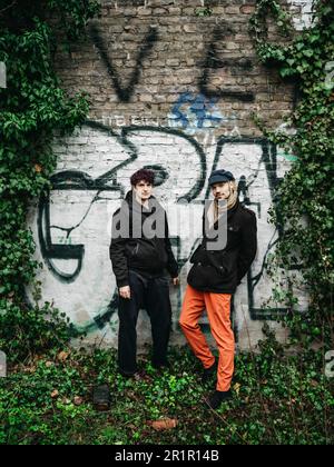 Couple non binaire devant le mur avec graffiti Banque D'Images