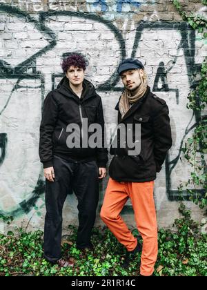 Couple non binaire devant le mur avec graffiti Banque D'Images