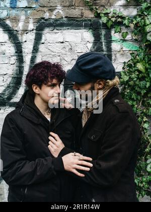 Couple non binaire devant le mur avec graffiti Banque D'Images