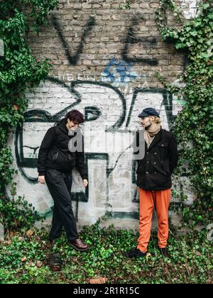 Couple non binaire devant le mur avec graffiti Banque D'Images