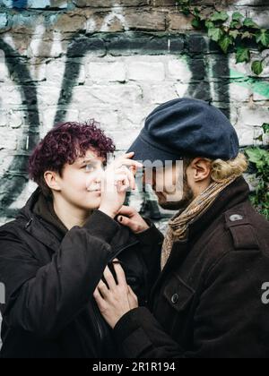 Couple non binaire devant le mur avec graffiti Banque D'Images