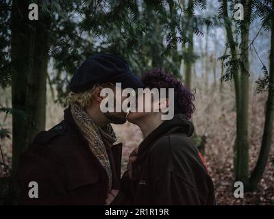 Couple non binaire embrassant dans la forêt Banque D'Images