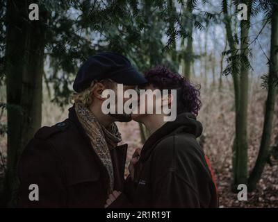 Couple non binaire embrassant dans la forêt Banque D'Images