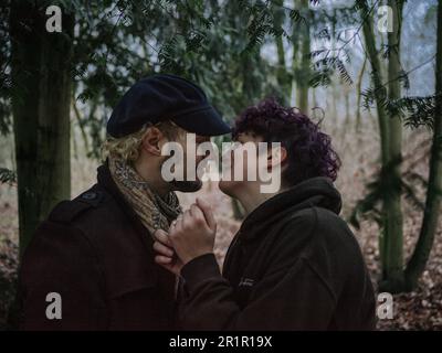 Couple non binaire embrassant dans la forêt Banque D'Images