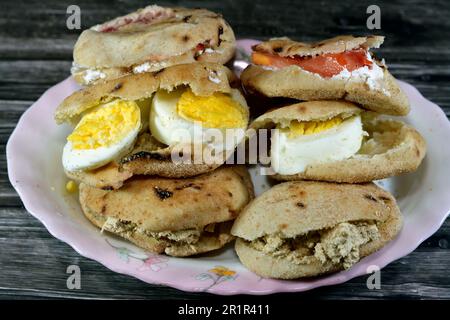 Une assiette de sandwiches au fromage blanc Feta avec des tranches de tomates, de la tahini halva traditionnelle ou Halawa Tahiniya et des tranches d'œufs durs insi Banque D'Images