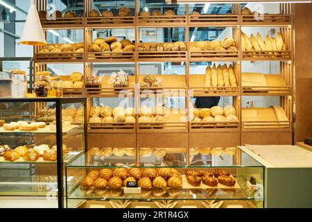 Comptoir du commis de boulangerie et étalages avec du pain frais et assortiment de pâtisseries vendus dans la cafétéria après la cuisson par boulanger professionnel Banque D'Images