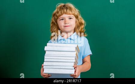 Pile de livres avec plaque de mortier sur tableau noir. Retour à l'école. Enfant en classe. Un enfant heureux contre un tableau noir vert. Éducation et Banque D'Images