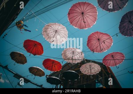 Une gamme de parasols suspendus dans l'air au-dessus d'une rue de ville, créant une verrière colorée Banque D'Images