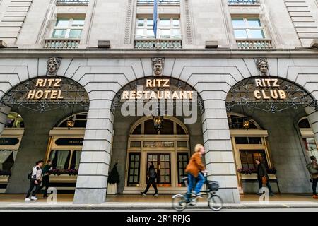 Londres - 2023 mai : l'hôtel de luxe 5 étoiles Ritz London avec les célèbres taxis noirs londoniens se déplace de façon floue devant l'entrée principale. Banque D'Images