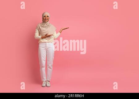 Promotion agréable. Femme musulmane souriante dans le hijab en train de piquer à côté de Copy Space Banque D'Images