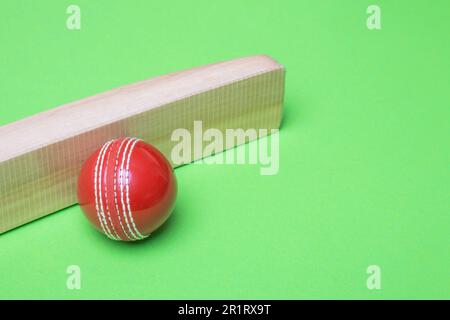 Batte de cricket et balles rouges sur fond vert. Affiche sur le thème du sport horizontal, cartes de vœux, en-têtes, site Web et application Banque D'Images