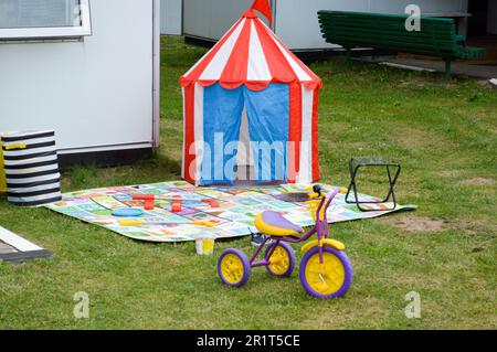 Aire de jeux pour enfants dans la cour de la maison sur pelouse avec une tente, une tente tricycle jouet. Banque D'Images