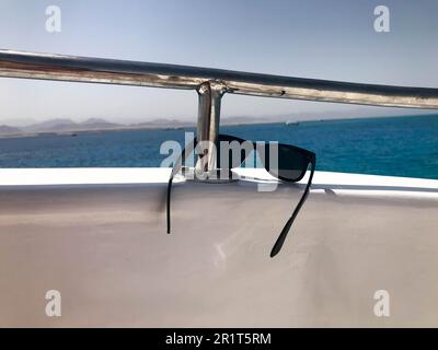 Des lunettes de protection en plastique noires sont suspendues sur le beryl à bord d'un bateau touristique, d'un yacht et d'un voilier, d'un bateau, d'un paquebot à la station, de la mer, sur un tr Banque D'Images