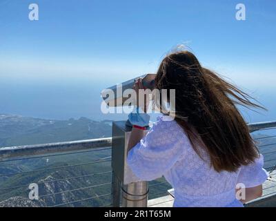 Hipster jeune fille avec sac à dos lumineux regardant sur la terrasse d'observation et planification de voyage. Vue de l'arrière du touriste. Banque D'Images