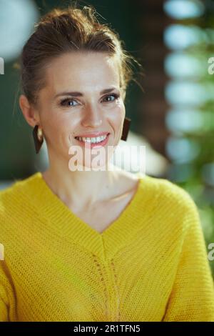 Portrait d'une femme heureuse et moderne propriétaire de petite entreprise en chandail jaune debout dans le bureau vert moderne. Banque D'Images