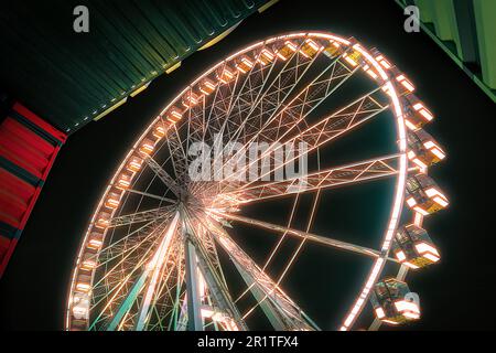 Une photo en petit angle d'une grande roue illuminée dans une zone urbaine la nuit Banque D'Images