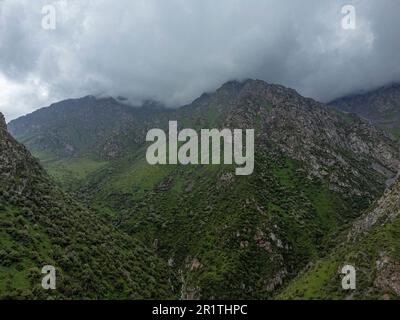 Vue aérienne voler à travers les montagnes couvertes de nuages dans la gorge d'Alamedin, Kirghizistan. Banque D'Images