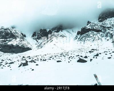 Magnifiques montagnes froides paysages de station d'hiver avec hauts sommets de brume et de neige couverts de rochers pour le snowboard et le ski contre un ciel bleu. Banque D'Images