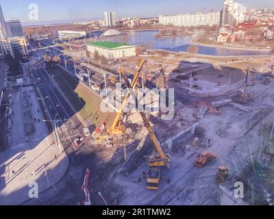 construction d'un nouveau passage supérieur dans le centre-ville. près de la rivière, chemin de randonnée et de nombreux bâtiments. grues hautes sur la route. Banque D'Images