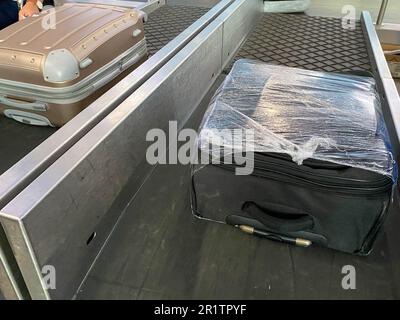une valise est posée sur une bande de bagage dans le hall des arrivées des passagers de l'aéroport, le concept de la récupération ou de la perte des bagages. Banque D'Images