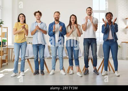 Les personnes amicales multiraciales dans des vêtements décontractés se tiennent à la ligne et applaudissent à vous regarder. Banque D'Images