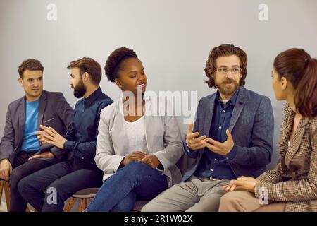 Groupe de jeunes gens d'affaires multiraciaux, hommes et femmes, assis au bureau et parlant Banque D'Images