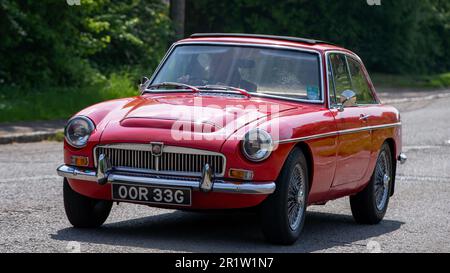 Stoke Goldington, Northants, Royaume-Uni - 14 mai 2023. 1968 voiture de sport classique MGC GT rouge traversant un village anglais Banque D'Images