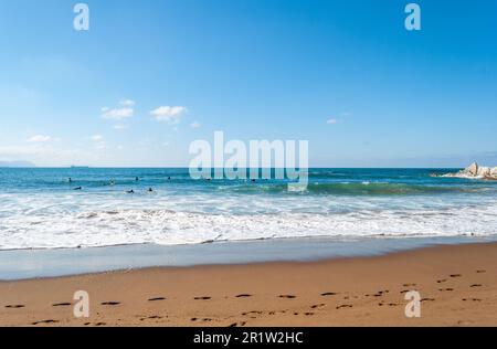 Les grandes vagues se brisent et créent de la mousse blanche qui se vaporise dans l'air. Plage de Sopelana près de Bilbao. Les surfeurs attendent la vague parfaite. Empreintes. Banque D'Images