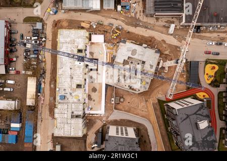 Photographie par drone d'un site de construction urbaine d'un complexe d'appartements à plusieurs étages au milieu d'autres structures pendant la journée ensoleillée du printemps. Directement au-dessus Banque D'Images