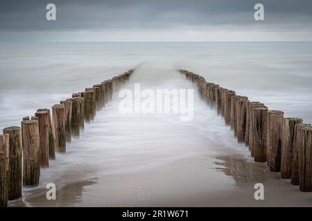 Brise-vagues sur la plage de Domburg aux pays-Bas. Photo longue exposition avec des vagues dynamiques se brisant sur le rivage sur des poteaux en bois Banque D'Images