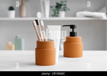 Porte-brosses à dents en bambou, savon et pâte sur table blanche dans la chambre Banque D'Images